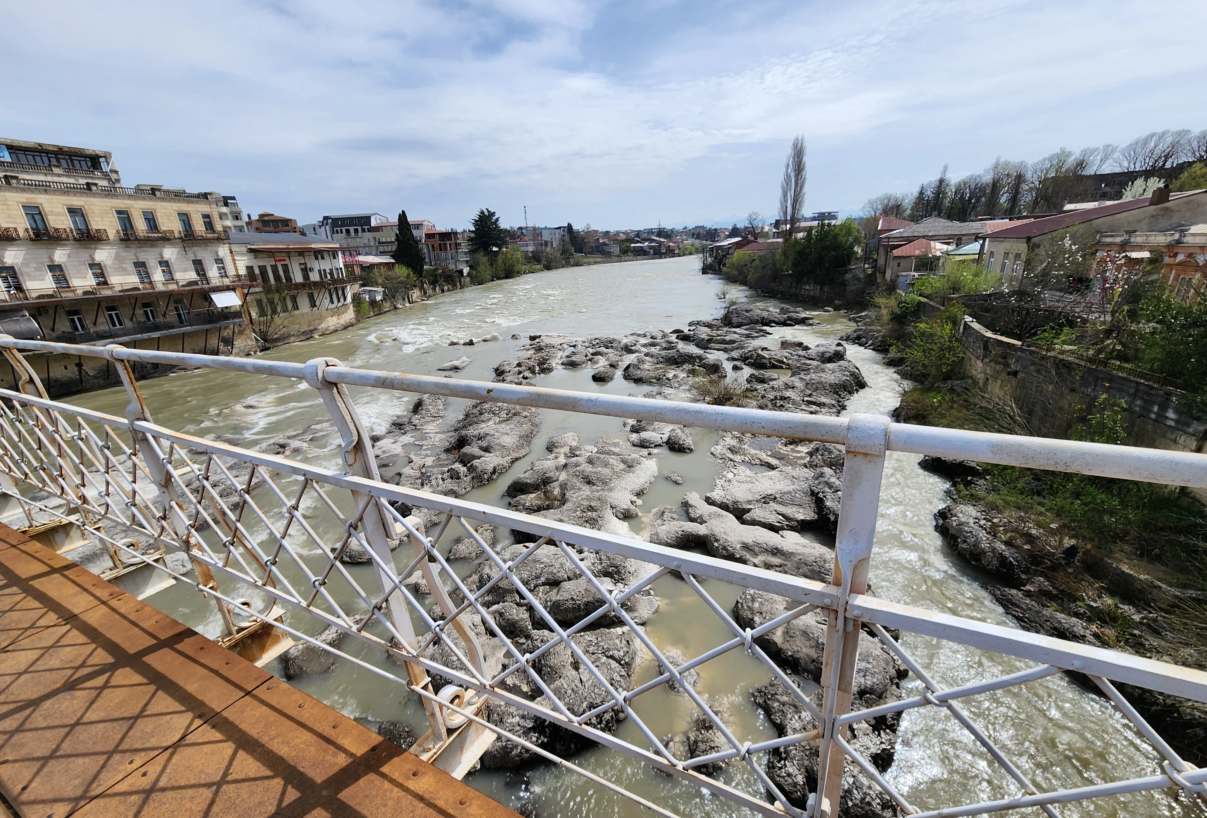 Rioni river seen from the White Bridge in Kutaisi: rocks and rapids, spring time in adjacent gardens