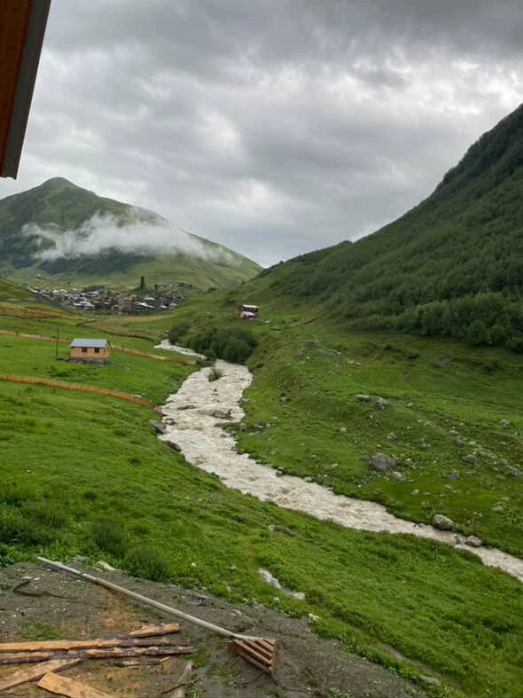 Rural area in svaneti - village in the distance - green hills divided by a small but raging river